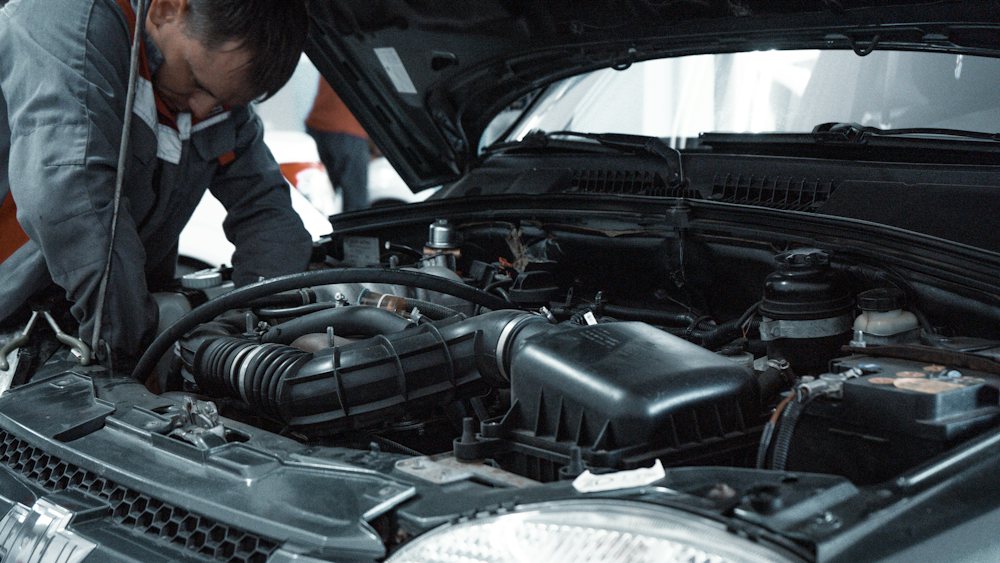 Mechanic inspecting a car engine bay with the bonnet raised