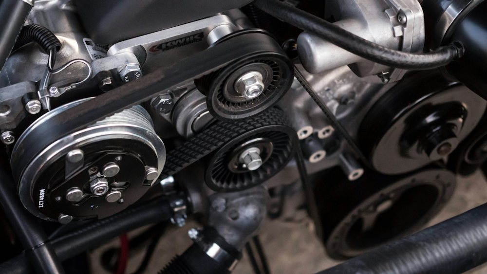 Close-up of an engine belt running over pulleys inside an engine bay