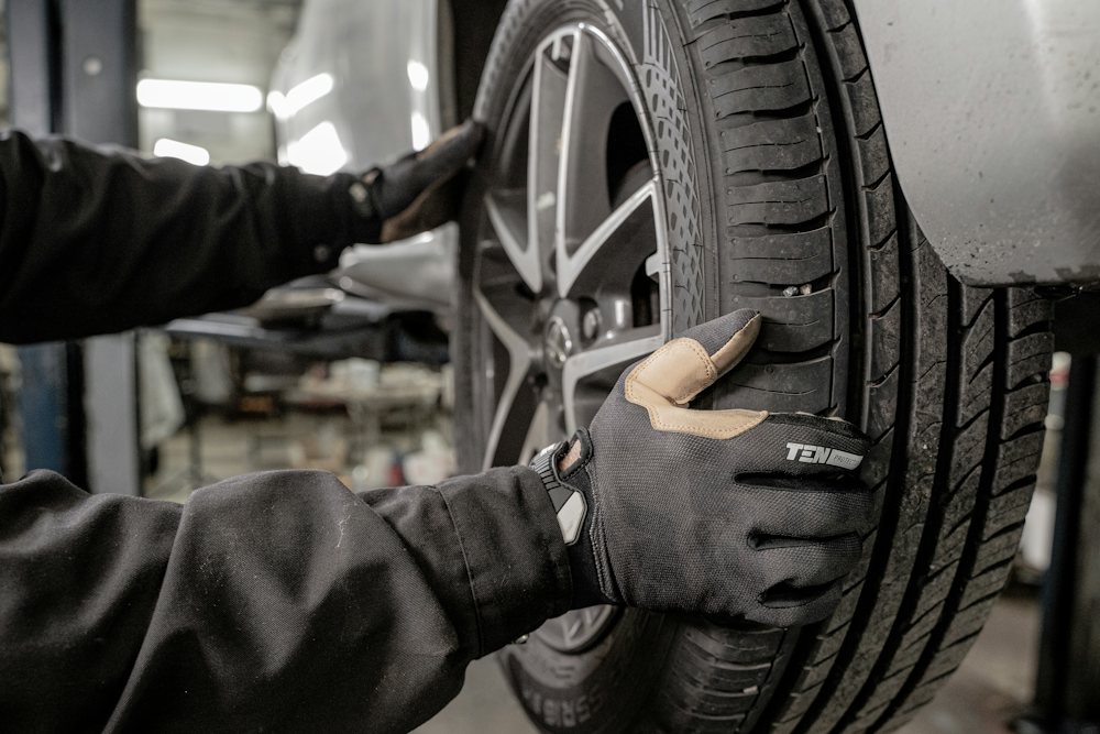Mechanic in gloves checking a car wheel and tyre